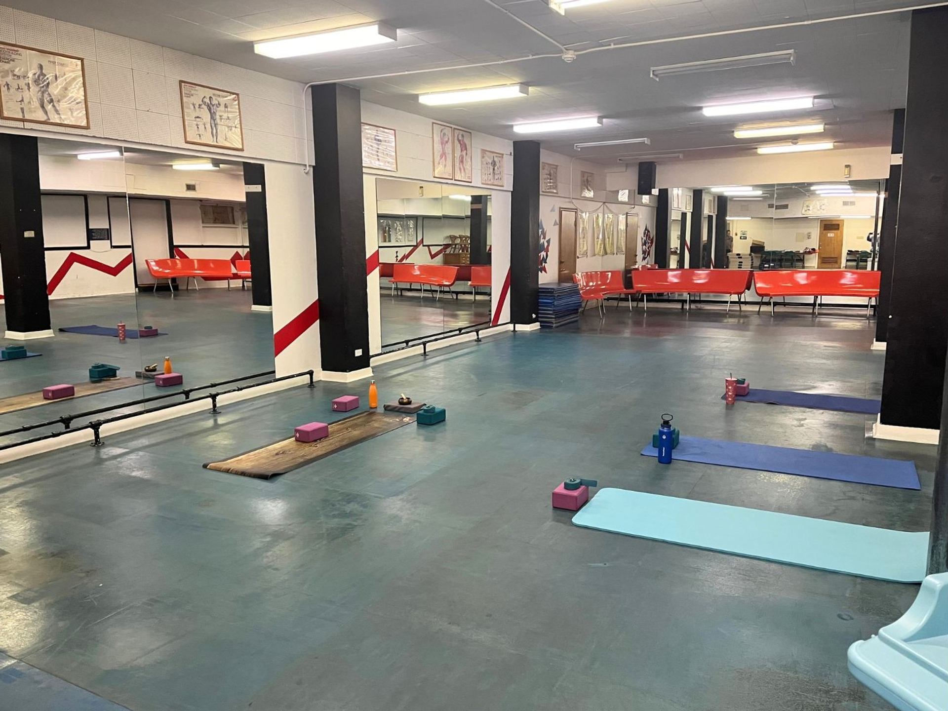 Exercise studio with yoga mats, blocks, water bottles and mirrored wall with posters