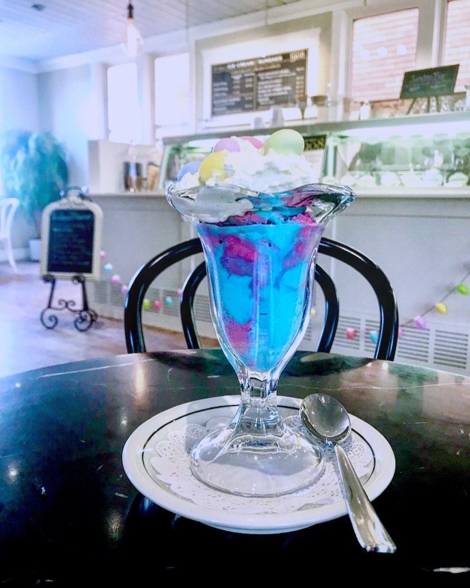 Vibrant blue ice cream sundae topped with whipped cream in a glass dish
