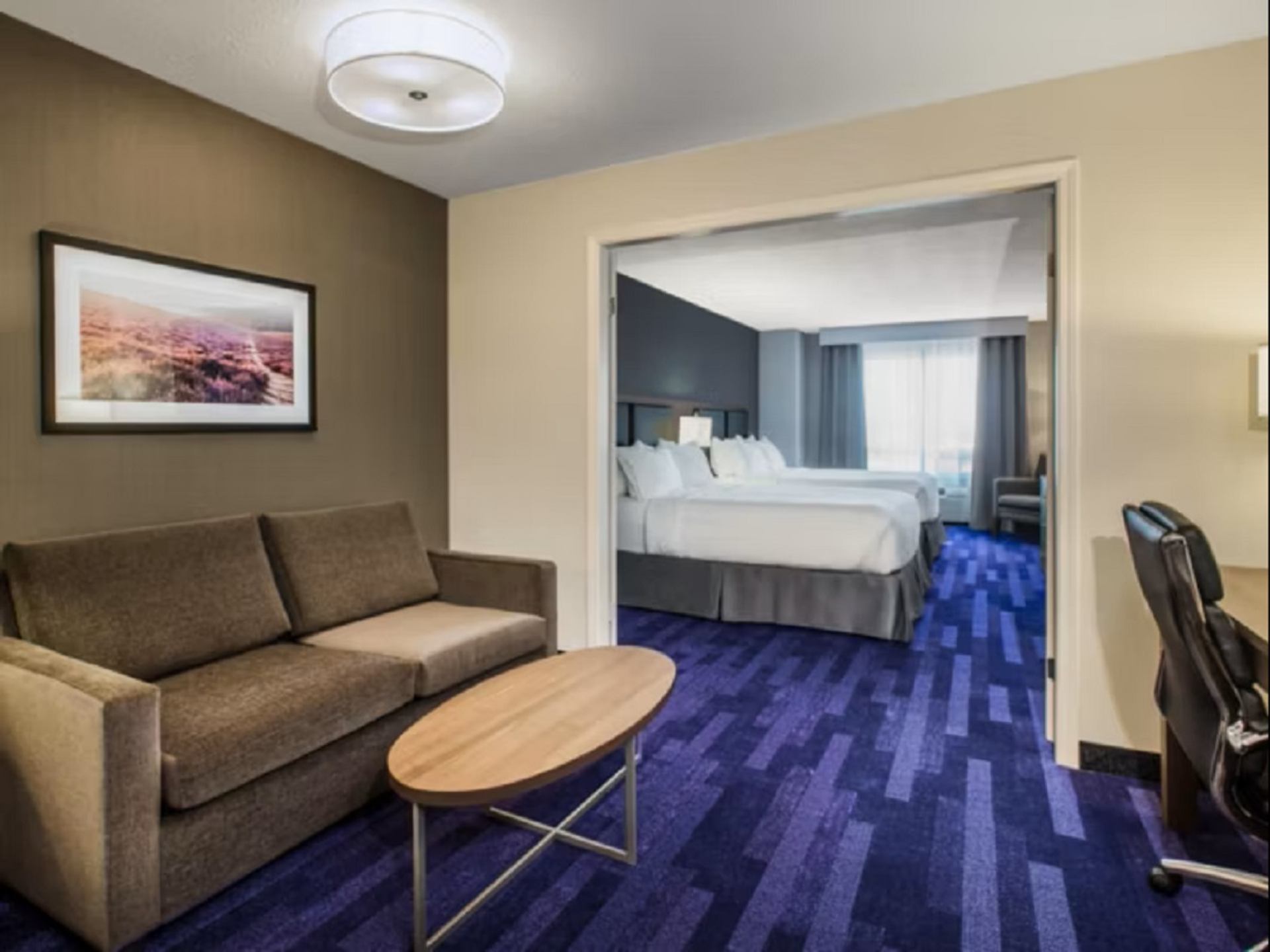 Hotel suite with sofa, coffee table, and two beds in a modern, cozy setting.