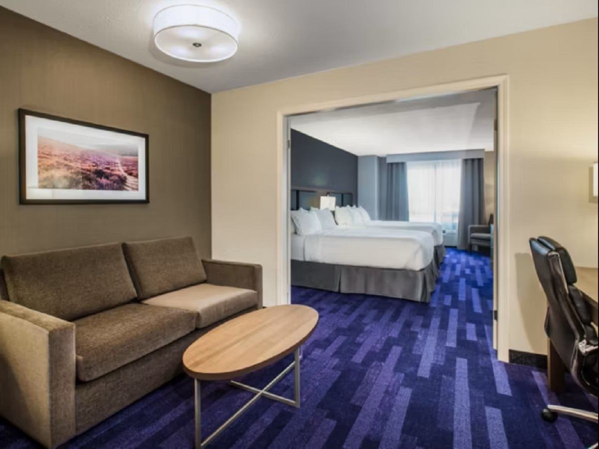 Hotel suite with sofa, coffee table, and two beds in a modern, cozy setting.