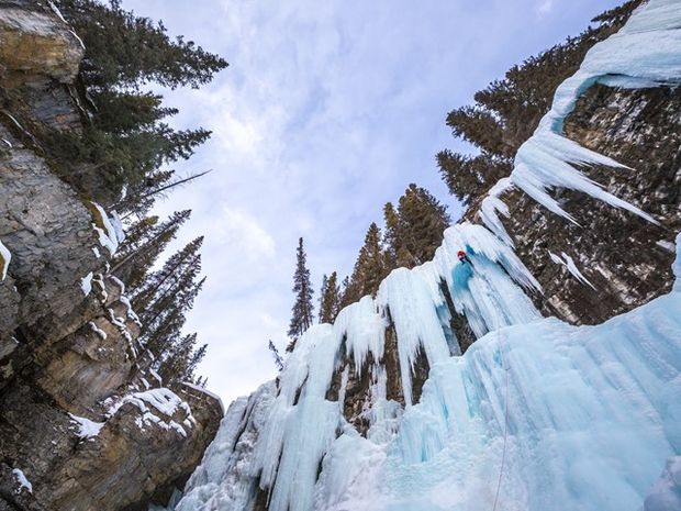 The view looking up at an ice climber at the top of an ice wall while ice climbing at Johnston Canyon.