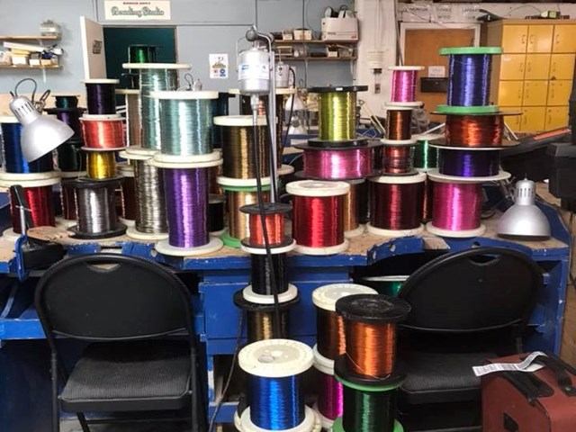 Workbench with colourful wire spools, chairs and lamps under Bedrock Supply sign.