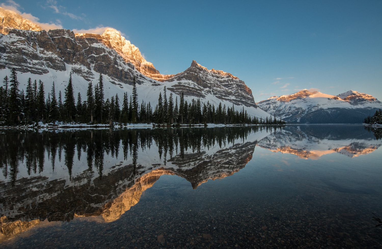 The rising sun shines on the mountains near Bow Lake in Banff National Park.