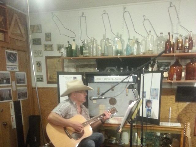 Person playing acoustic guitar at Holden Historical Society Museum event.