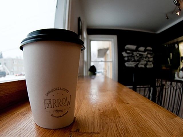 Farrow coffee cup on counter in cozy café with natural light and seating.