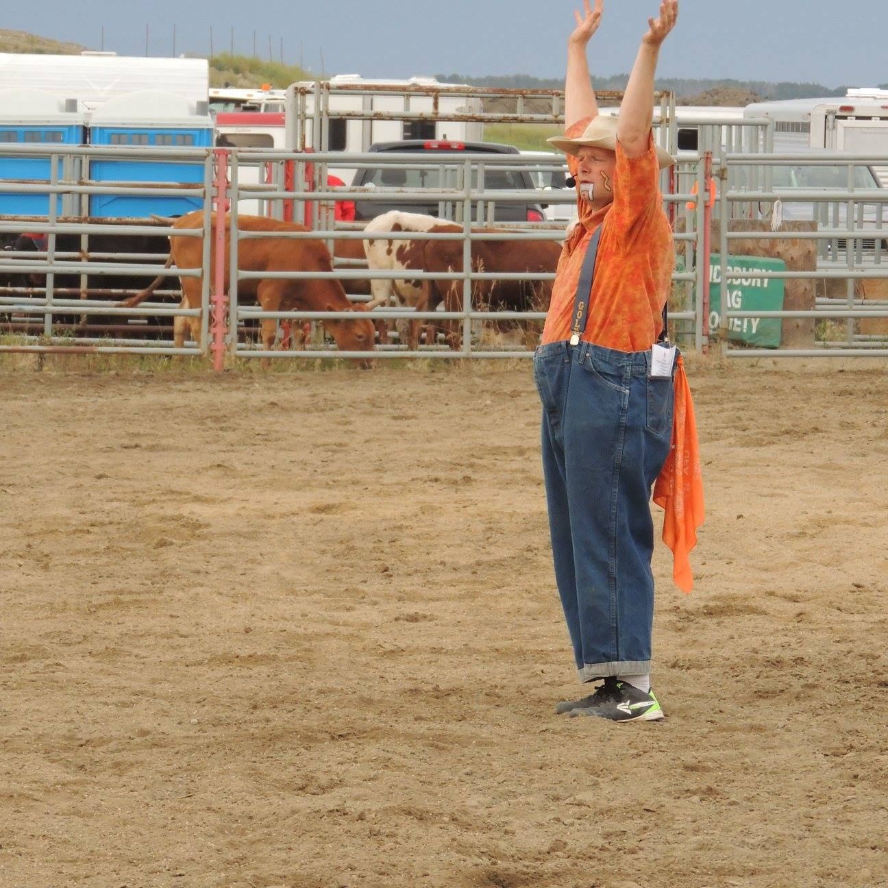 A rodeo clown with his hands above his head