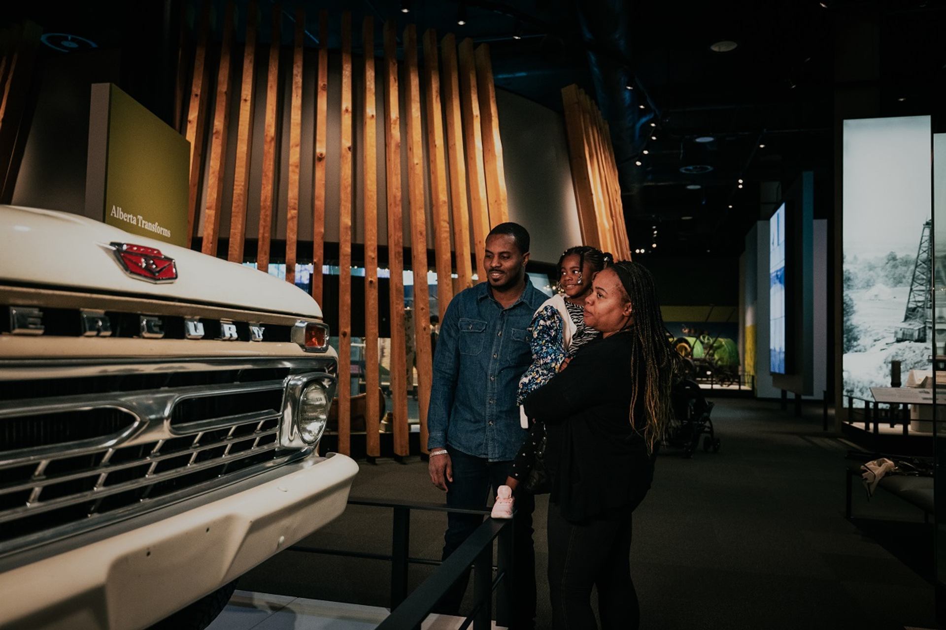Family viewing a vintage vehicle display inside the museum.