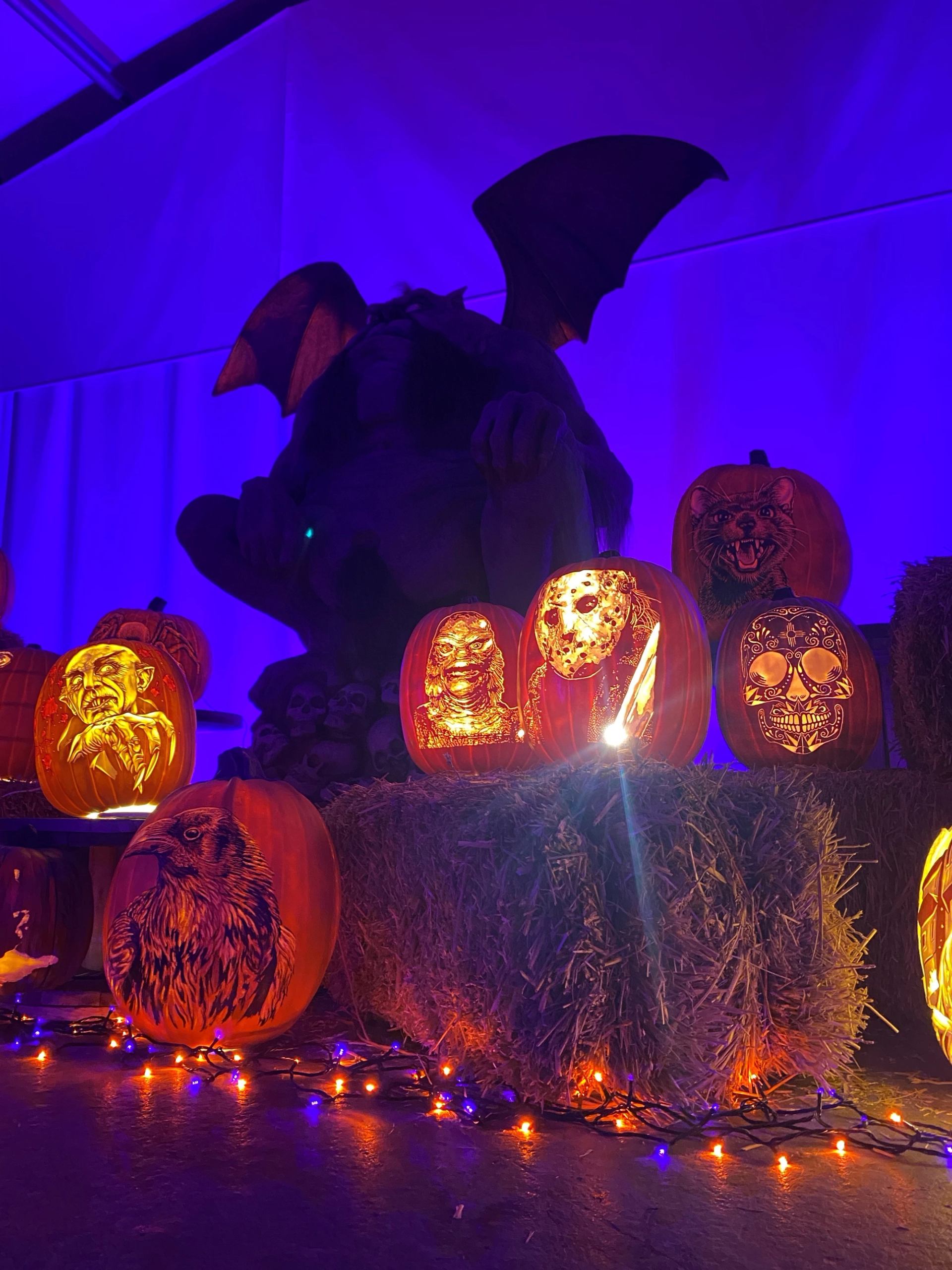Glowing pumpkins and winged statue in spooky Halloween night display.