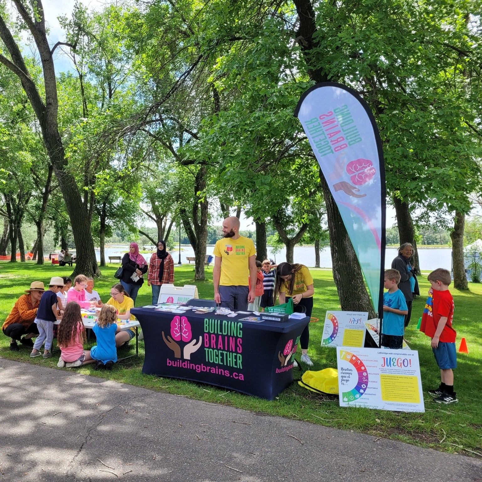 Outdoor Building Brains Together booth with children doing activities at tables in a park.