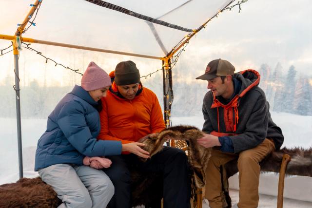 A guide from Mahikan Trails shares knowledge of the furs that are in the stargazing tent to participants on the guided experience.