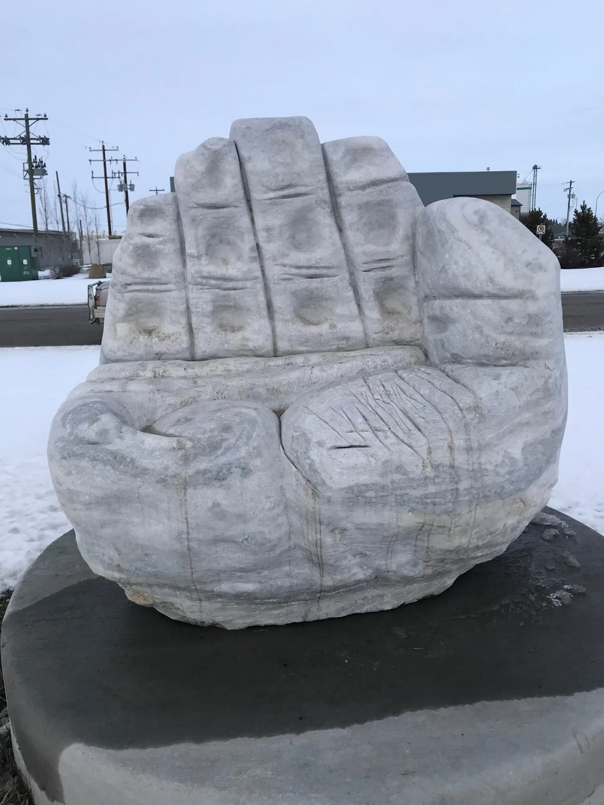 A stone sculpture of a hand hold a small pearl.