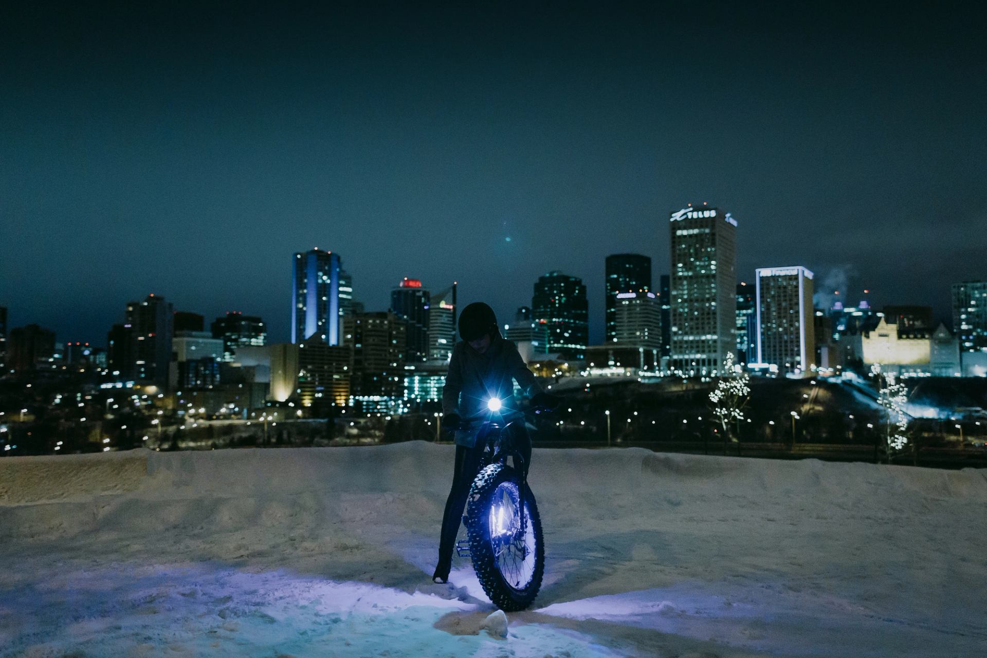 A fatbiker posing at night in front of the River Valley in Downtown Edmonton