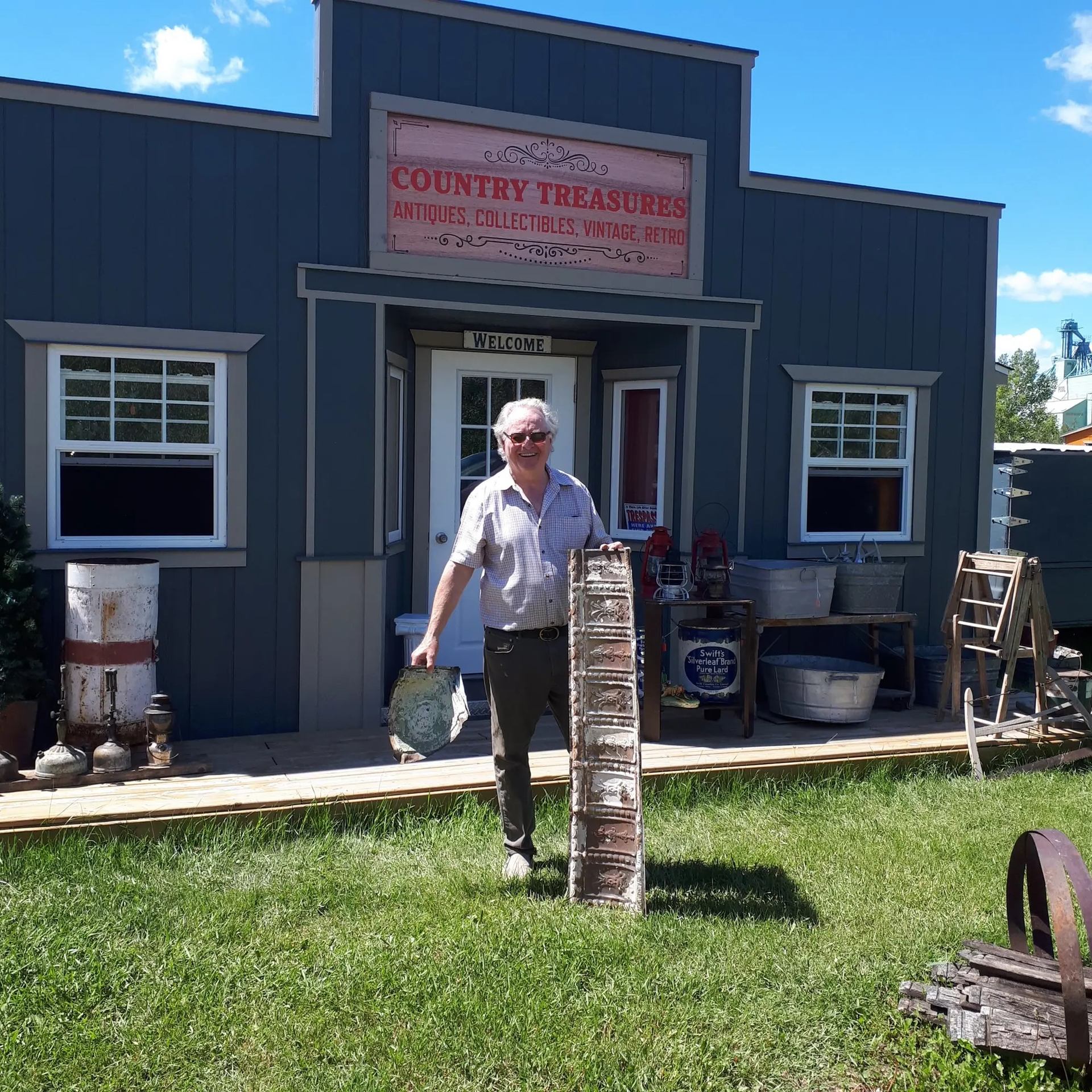 Person stands outside rustic shop “Country Treasures” with antiques and collectibles.