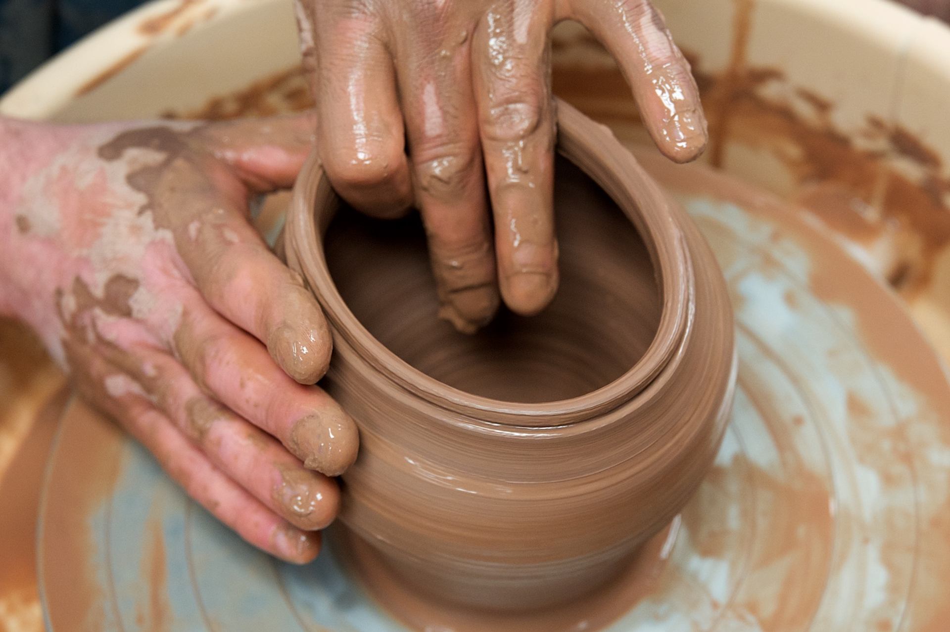 Hands shape clay on pottery wheel at Peace River Art Club class.