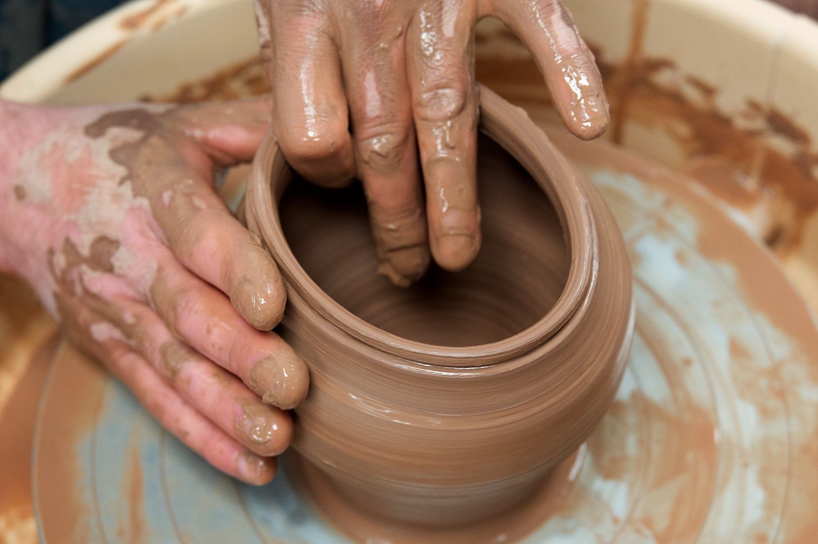 Hands shape clay on pottery wheel at Peace River Art Club class.