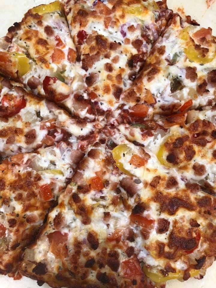 Pizza with cheese, pepperoni, vegetables, and olives, baked with browned crust.