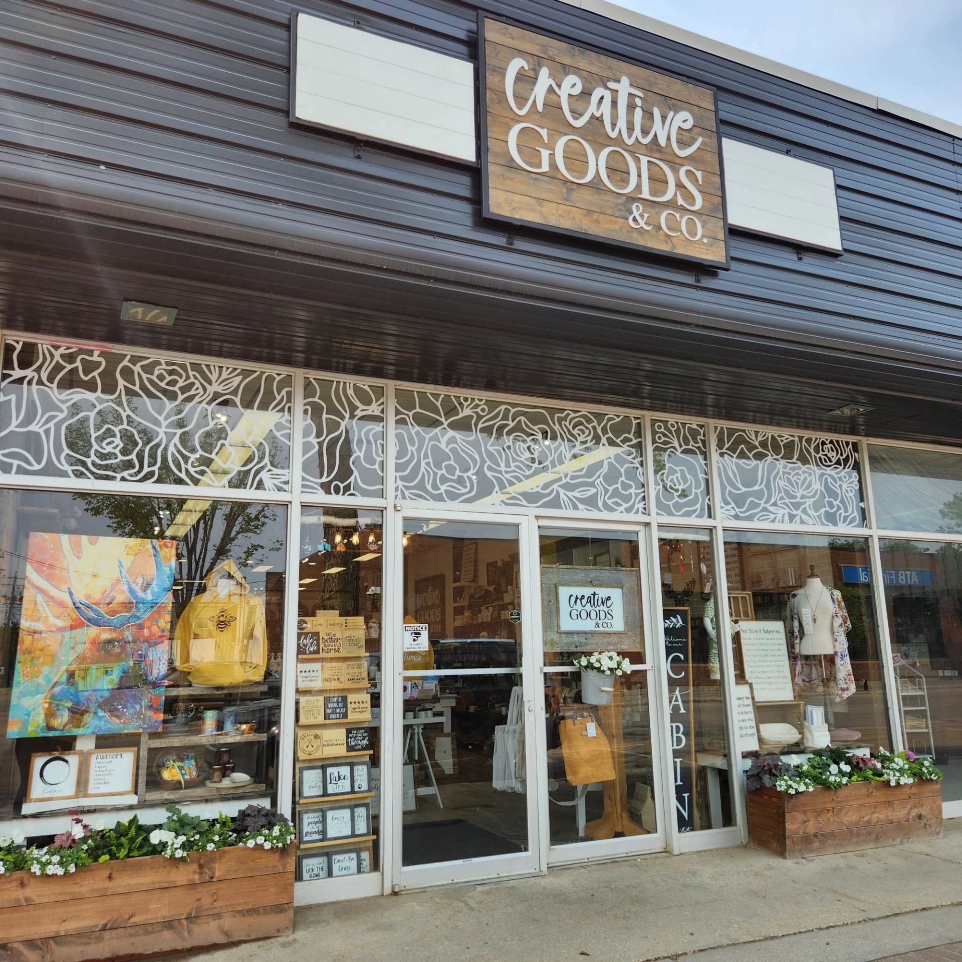 Creative Goods & Co. storefront with glass windows, wood sign, and floral planters.