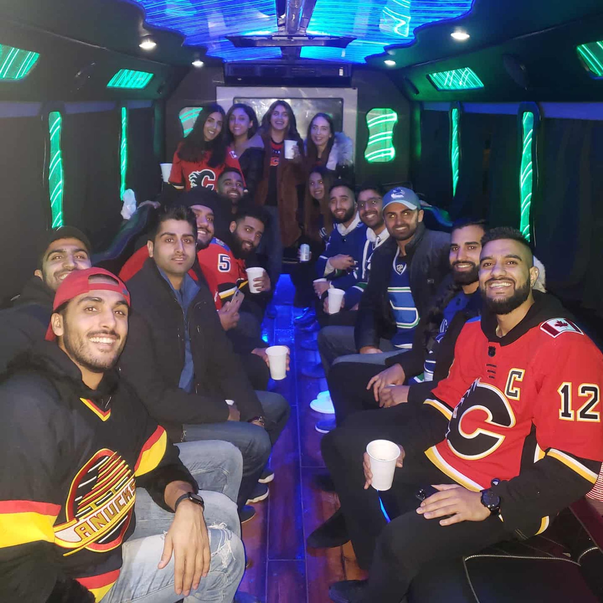 Group in hockey jerseys partying in a bus with blue and green lights.
