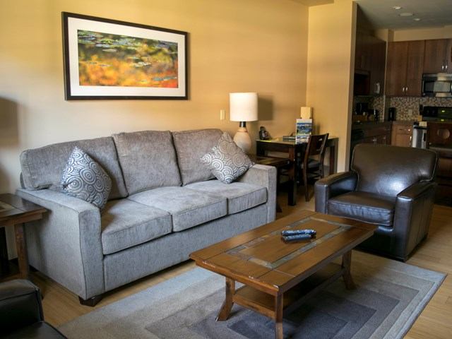 Modern lodge living room with sofa, coffee table, and open kitchen in background.