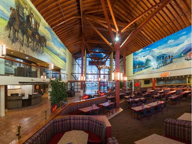 Spacious restaurant with murals and wooden beams at Super 8 Sherwood Park.