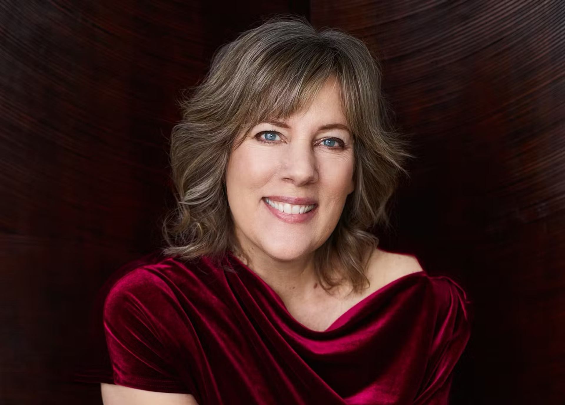Person in red velvet dress against dark textured background.