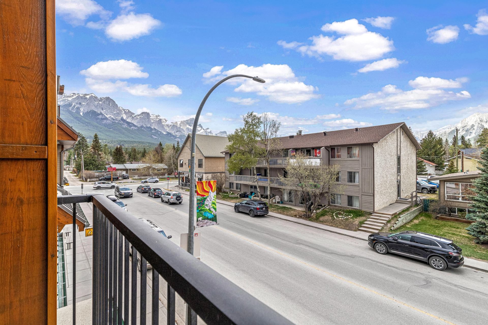 View from balcony overlooking street, buildings, and mountain peaks in the distance.
