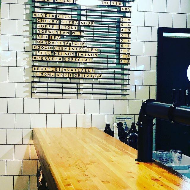 Brewery wall taps display beer names, ratings, and bottles on a bar counter.