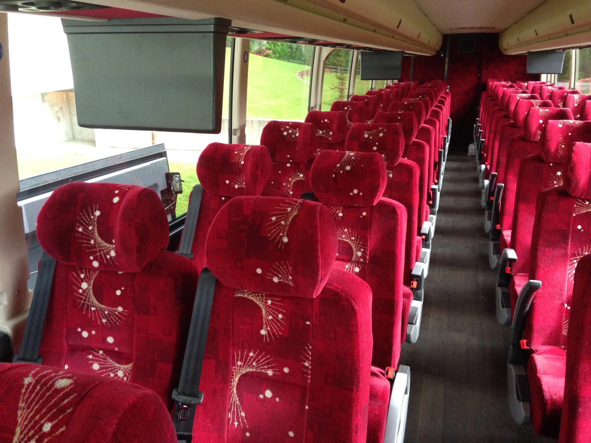 Interior of Sunshine Coach bus with red patterned seats and central aisle.