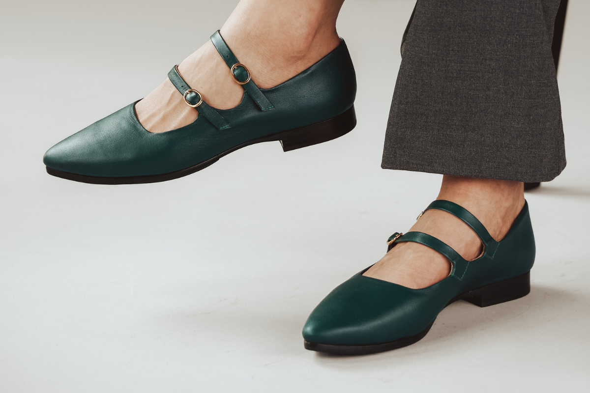 Green Mary Jane shoes with double straps, worn with gray pants.