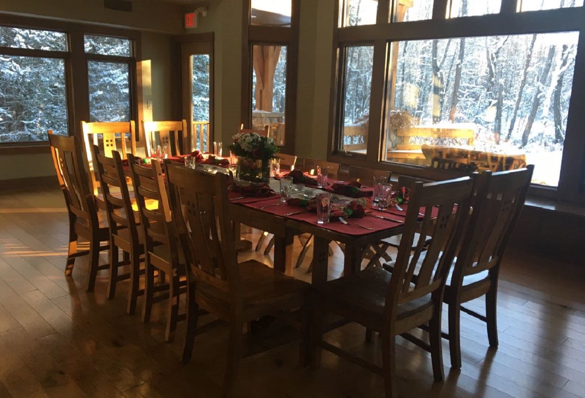 Long dining table set for a group with forest views at Spiritwood Retreat.