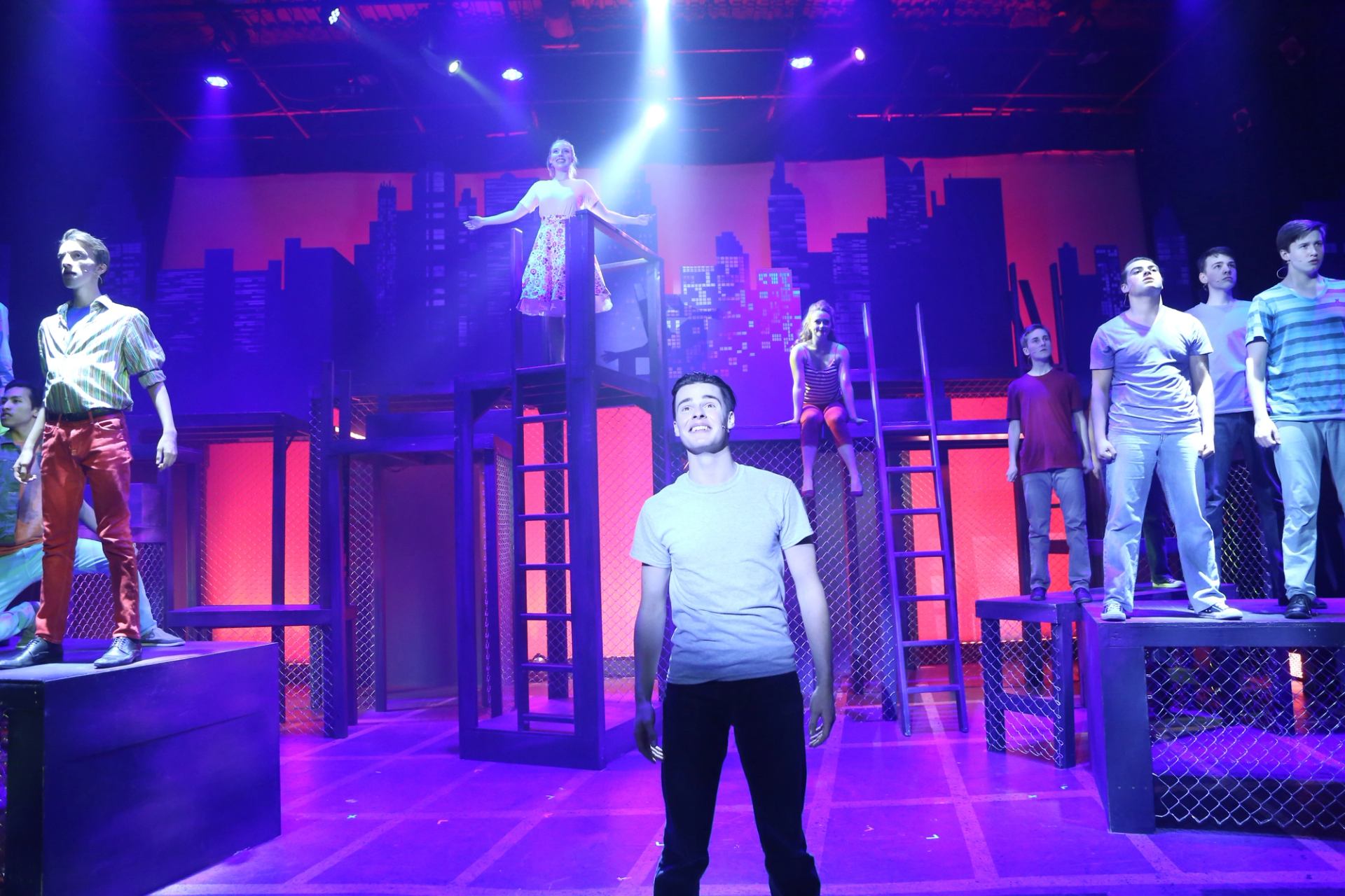 Storybook Theatre cast on multi-level cityscape set with dramatic lighting.