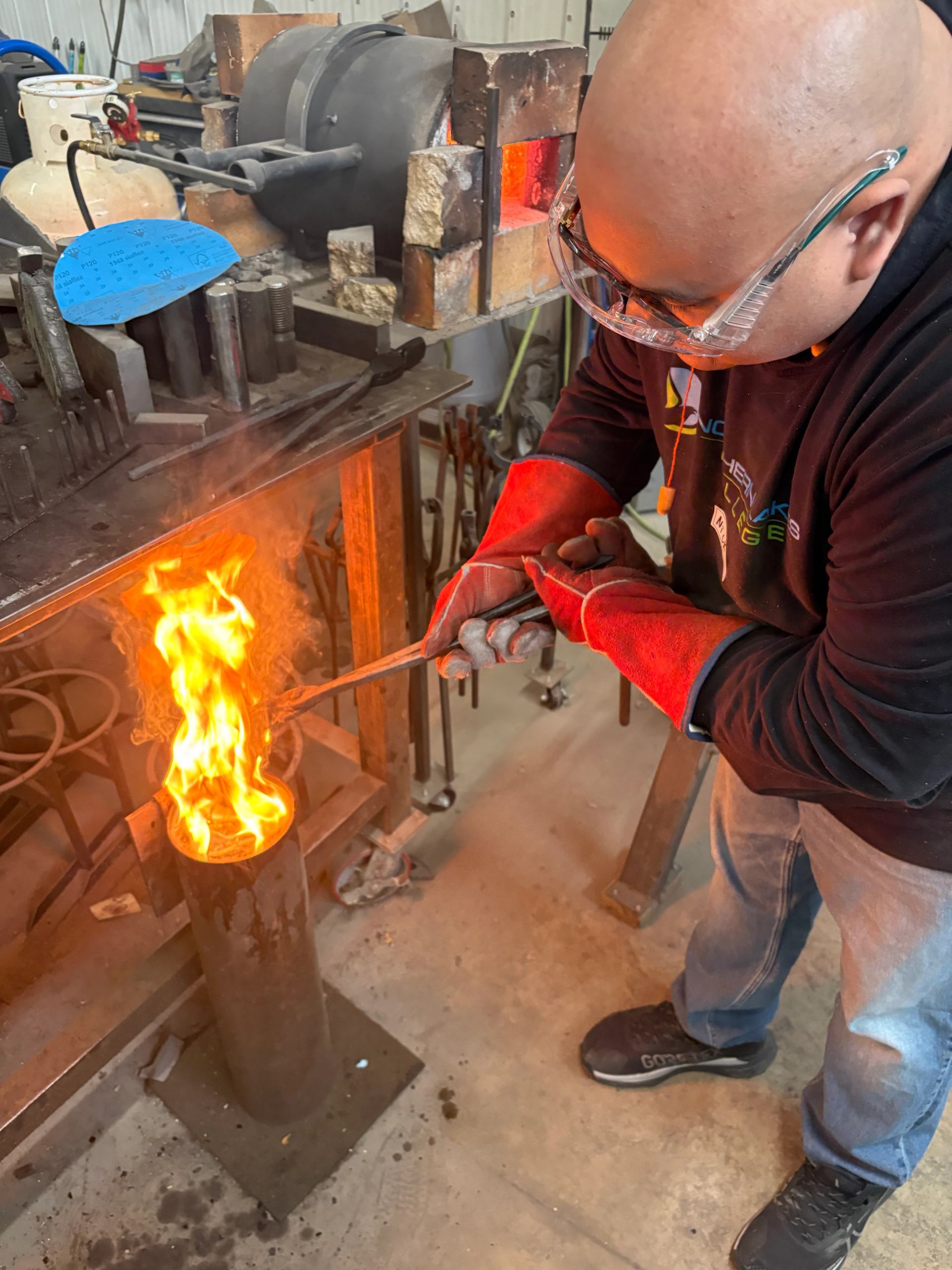 Person quenching hot steel in a flame during a knife making class.