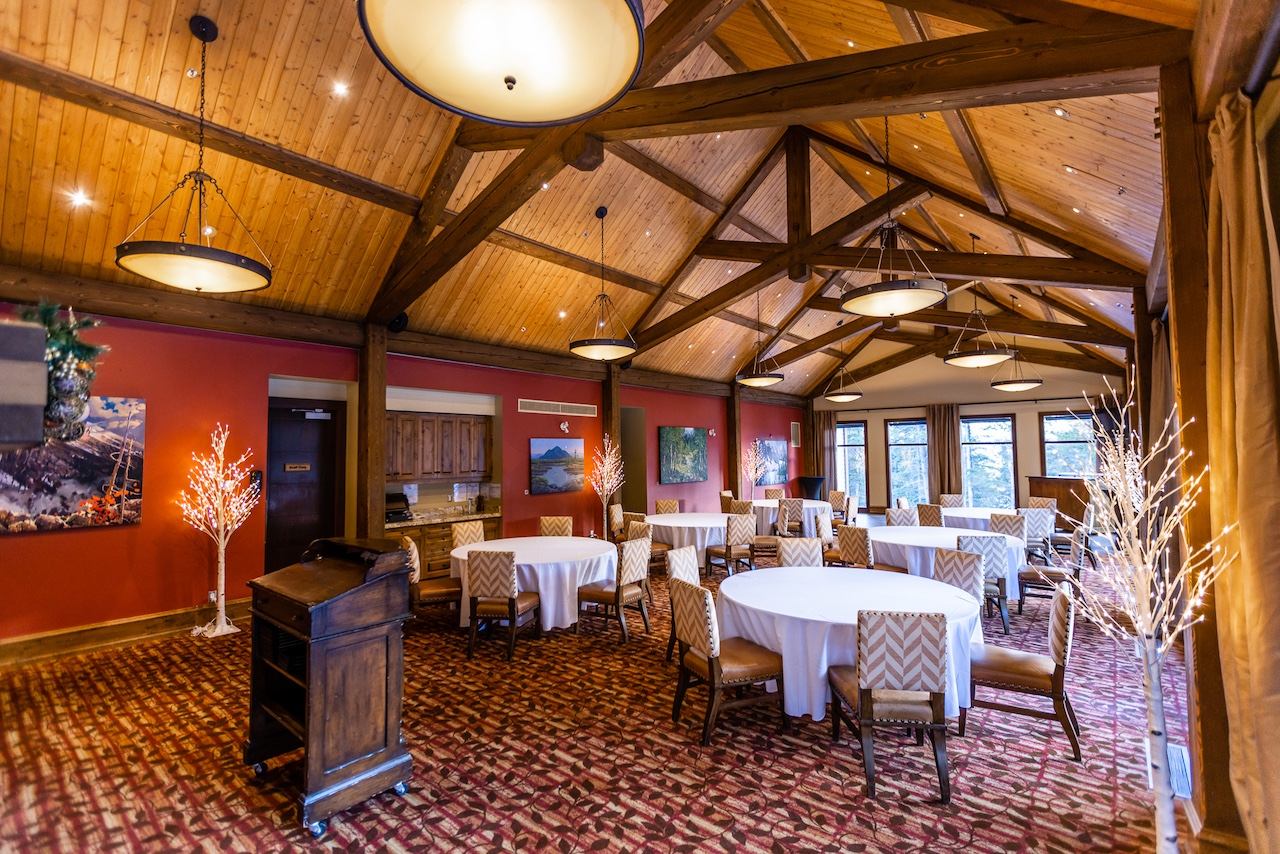 Indoor room with round tables, wood beams, and warm lighting.