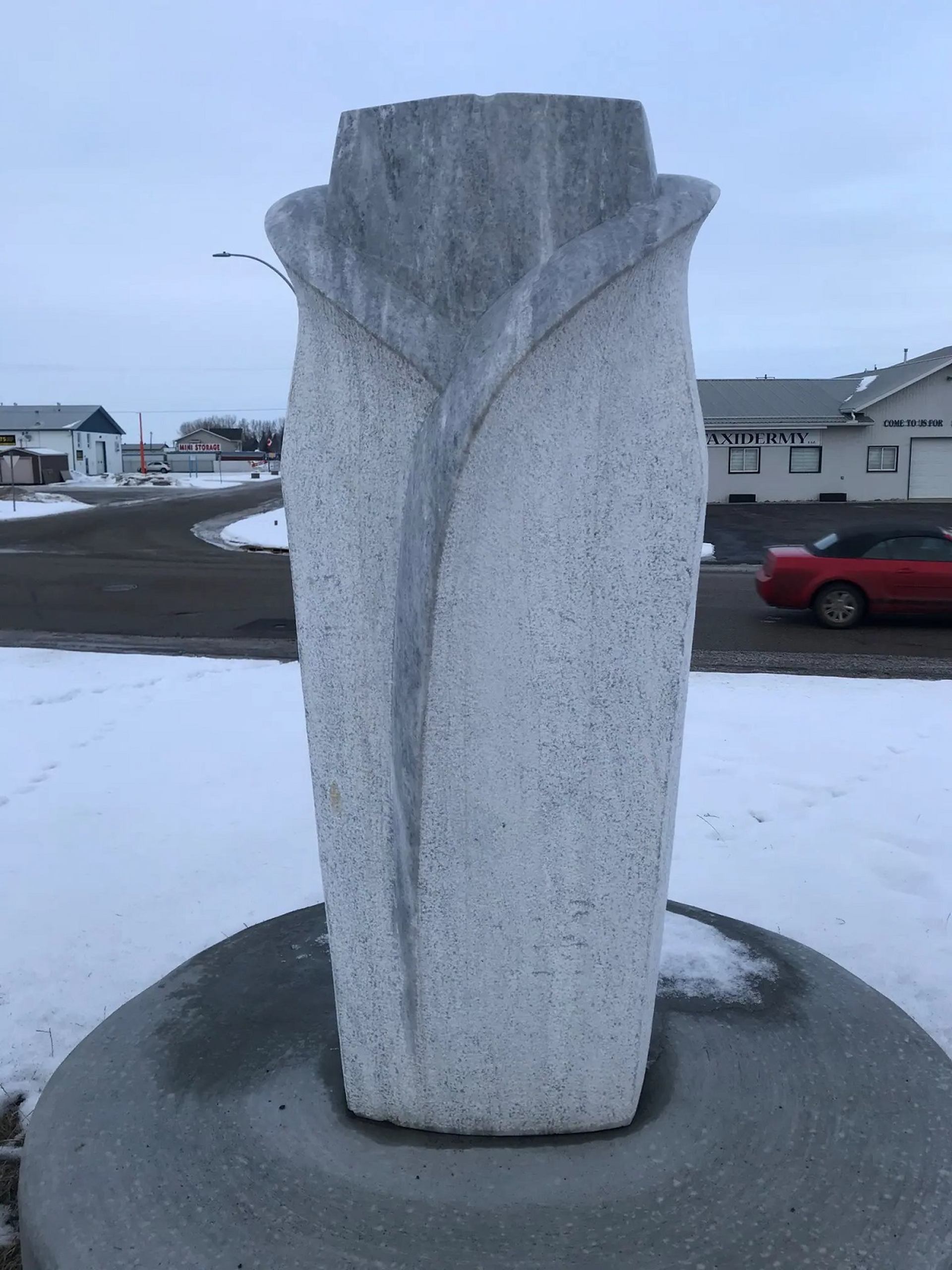 Stone sculpture represents a flower and a womans torso.