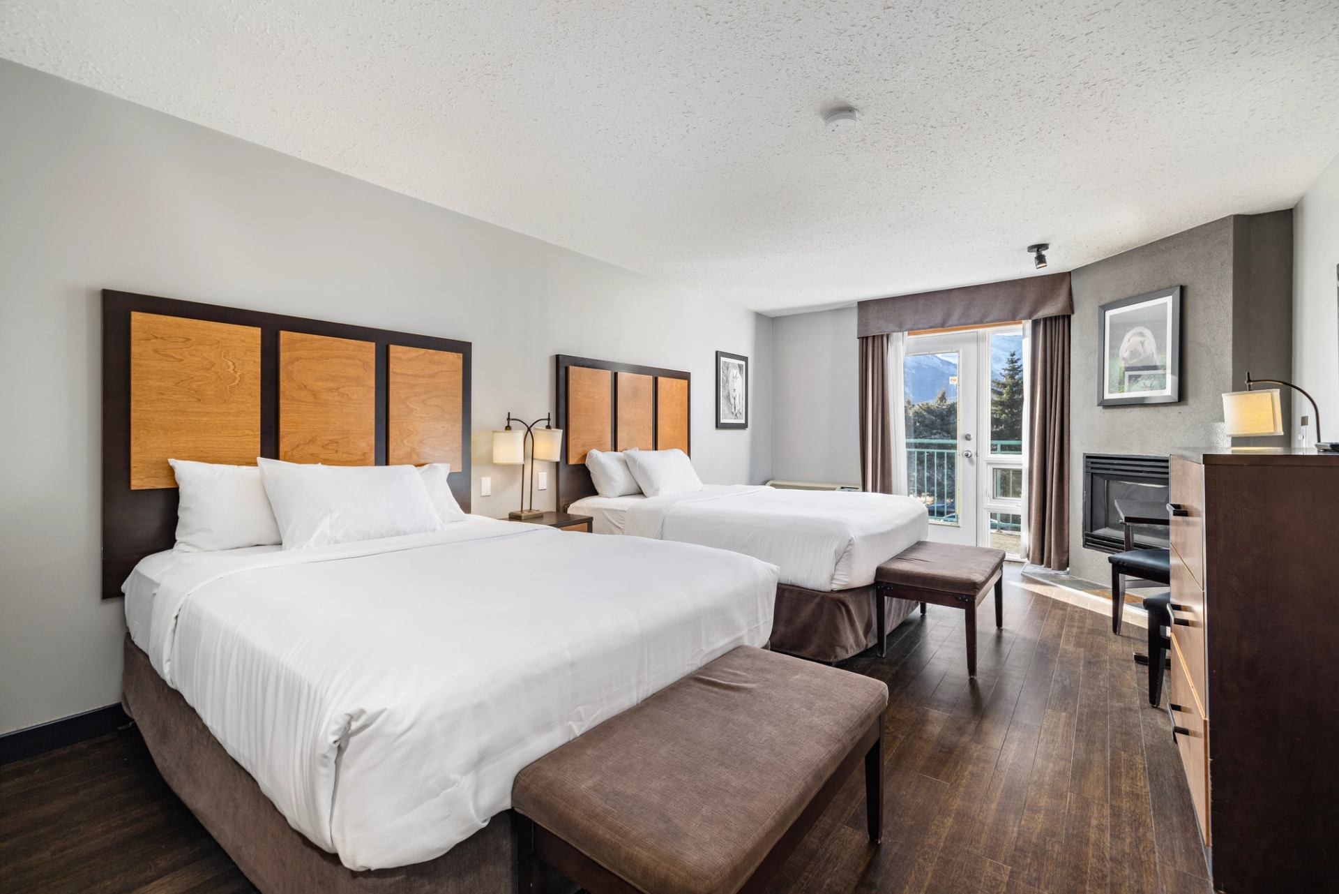 Hotel room with 2 beds with orange headboards, a fireplace in the corner and a balcony with blue sky