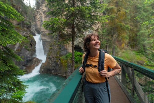 A shot of person smiling while they look around Johnston Canyon.