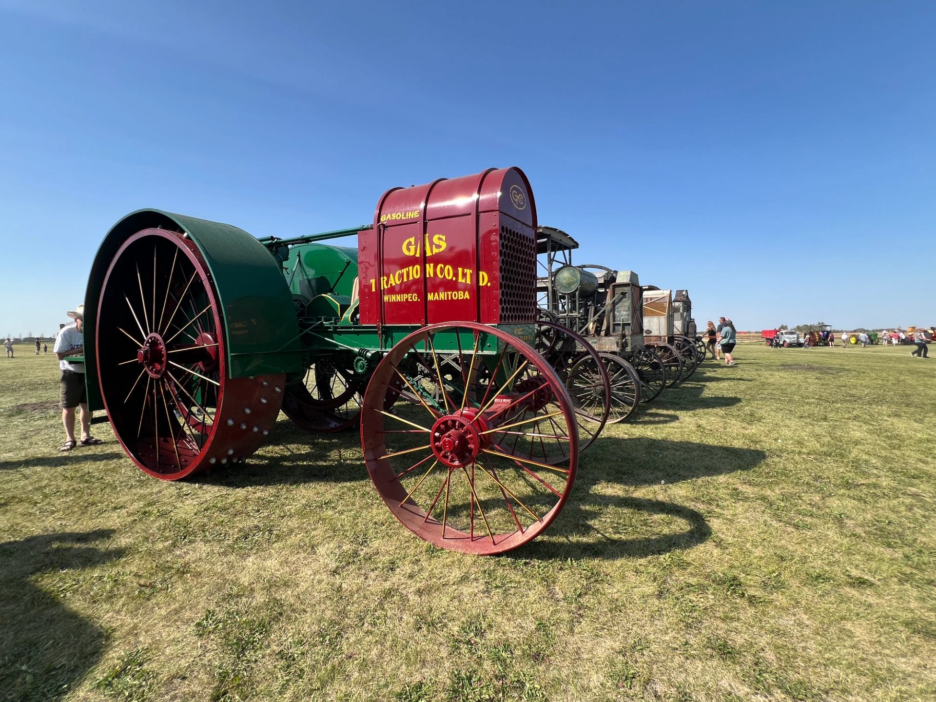 Row of antique tractors on display in an open grassy field.