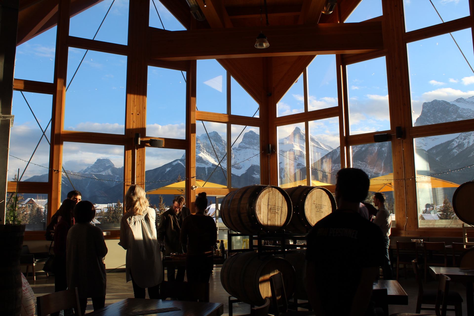 Interior of The Grizzly Paw Brewing Company with wooden barrels, large windows, and mountain views.