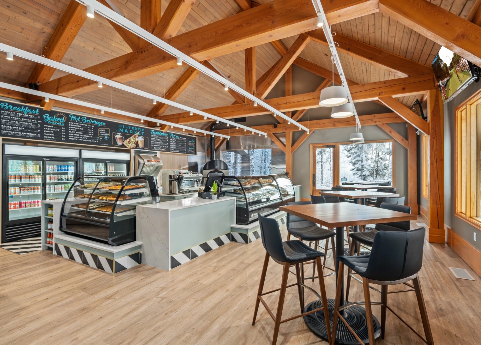 A café-style space with display cases, menu boards, and seating by large windows.