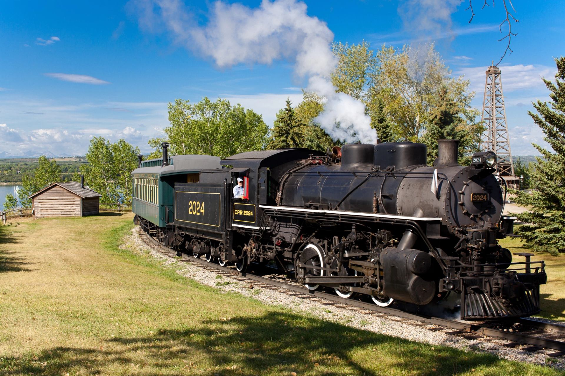 Steam train 2024 pulls green car on curved track at Heritage Park.