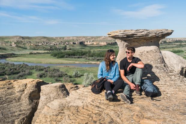 Couple taking a break and sitting on rocks at Writing-on-Stone Provincial Park in Southern Alberta.