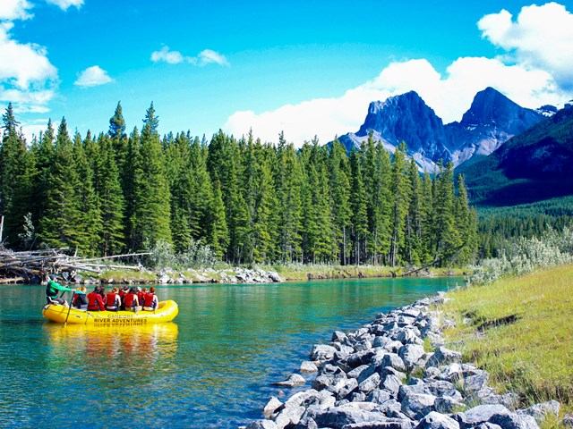 Rafting group on river with forest and mountain views.