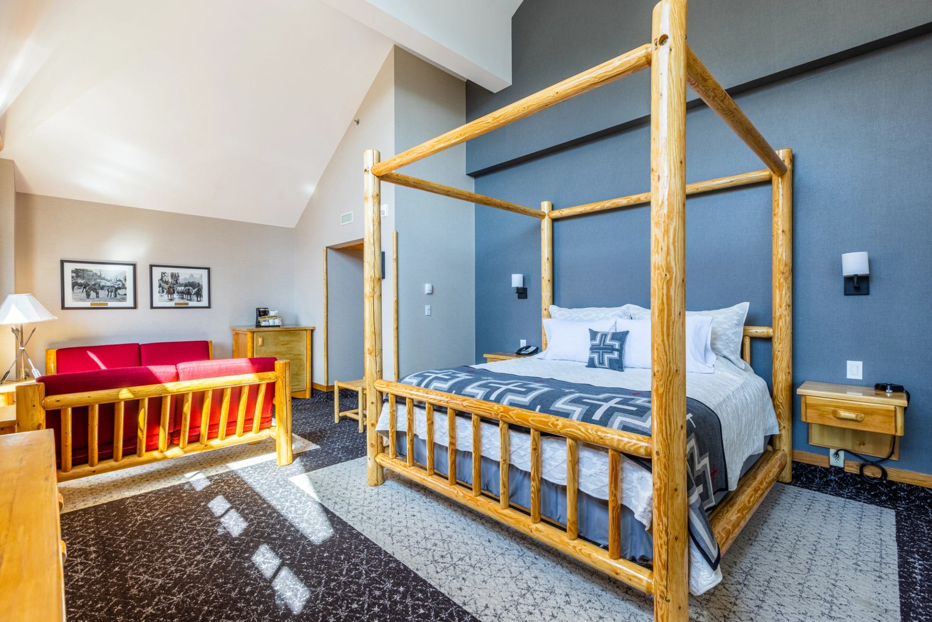 Spacious lodge room with four-poster bed, red sofa, and rustic-modern decor.