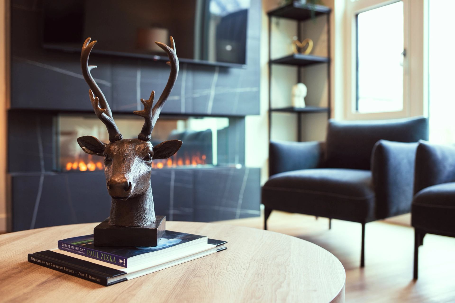 Close-up of a cozy lounge with deer sculpture, modern chairs, and a sleek fireplace.
