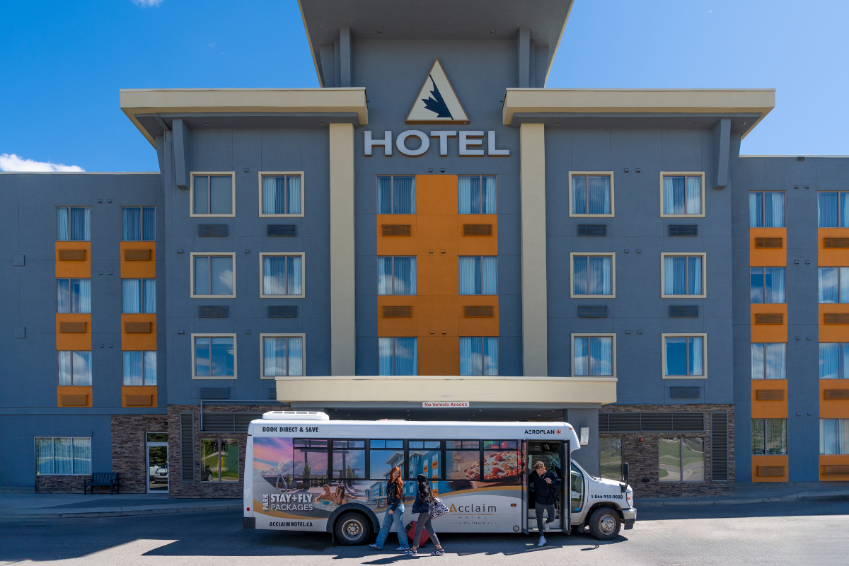 Exterior of the hotel with a couple stood in front of the shuttle bus.