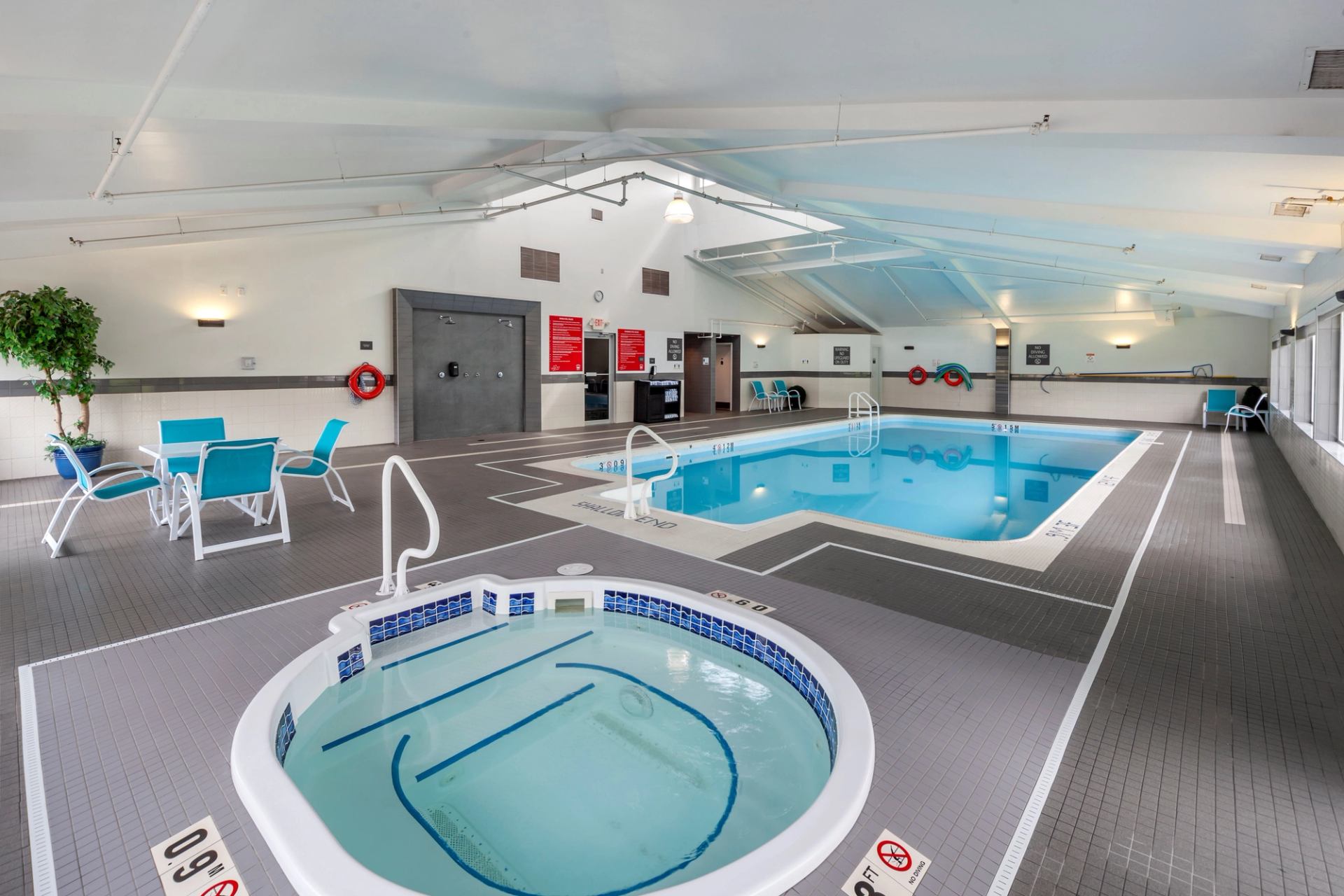 Bright pool and hot tub area with loungers.