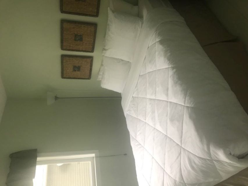 Bed with white duvet and pillows in a cabin bedroom with framed wall decor.