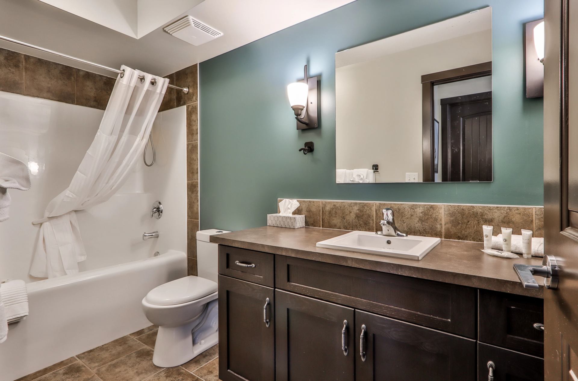 Clean, modern bathroom with large vanity, mirror, and shower‑tub combo at Scenic Mountain Resort.