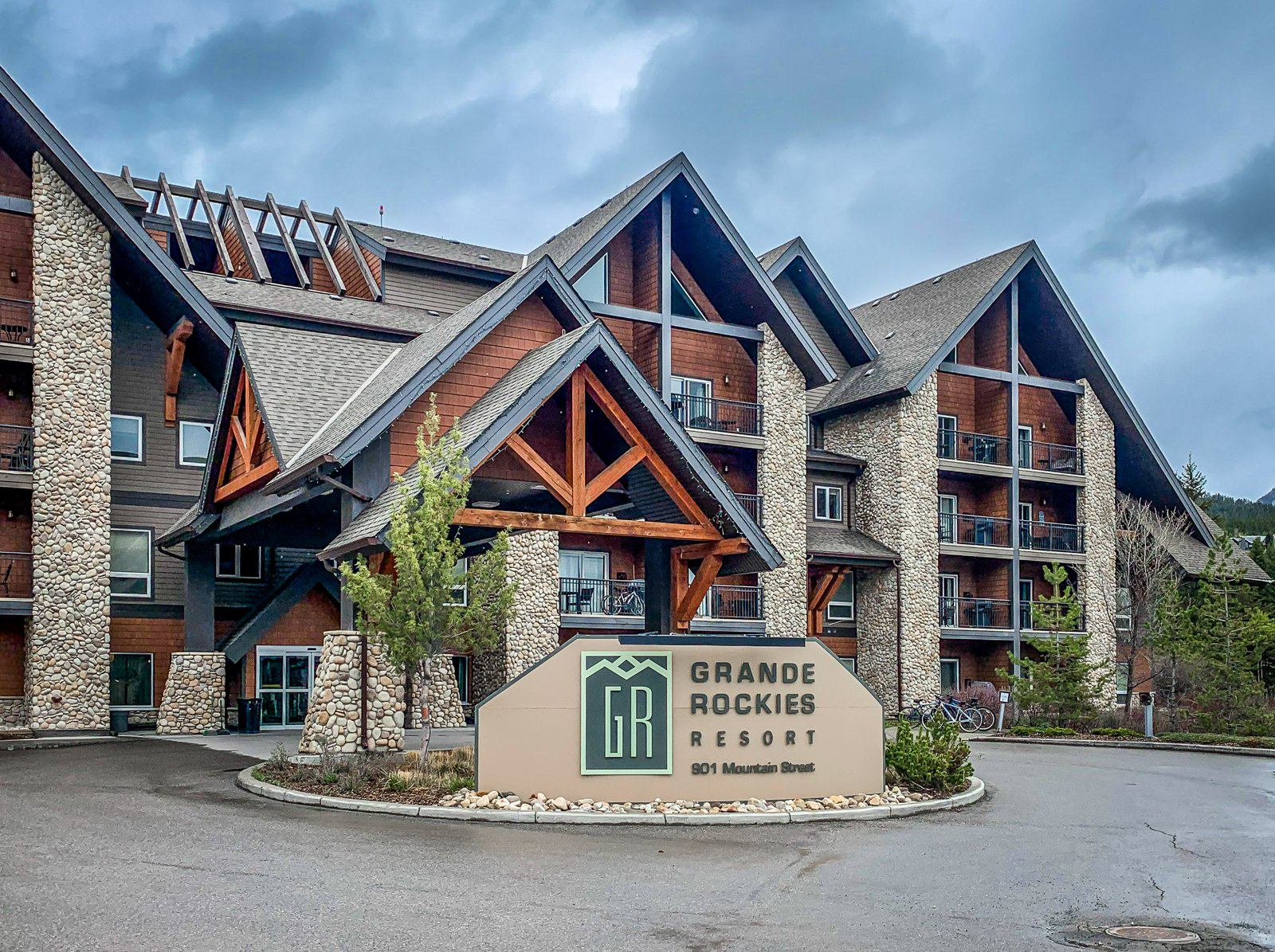 Grande Rockies Resort sign outside a stone-and-timber building with balconies.