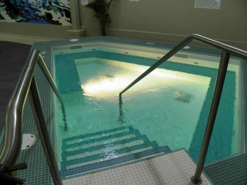 Indoor swimming pool with stainless handrails and tiled steps at Beaverlodge Recreation Centre.
